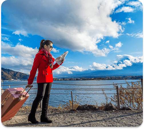 Traveller with a suitcase checking a map beside a lake