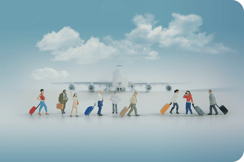 Miniature figures wheeling suitcases towards a model aeroplane